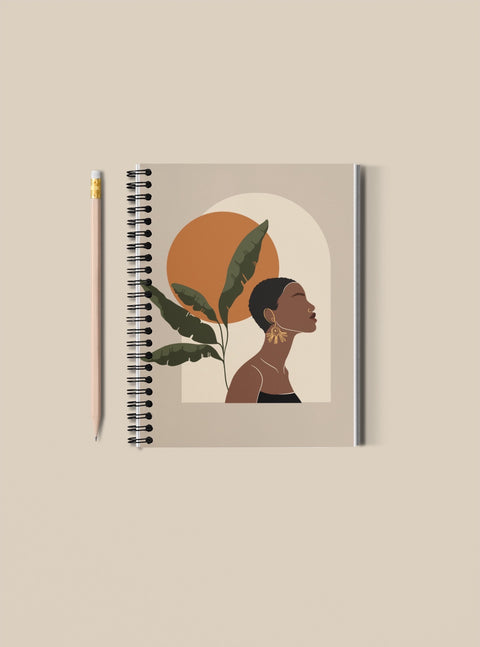 spiral bound notebook with image of black woman gazing confidently upward in sky with autumn sun; featured on plain background 