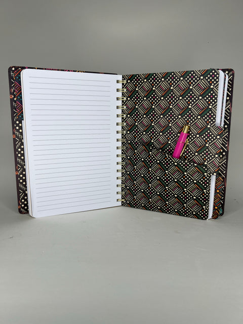 Open spiral notebook displaying lined pages and African tribal print tab divider with colorful pen inside pocket folder
